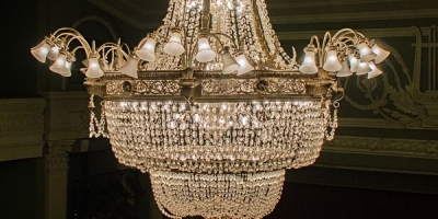a chandelier suspended above a theater's stage and box seats