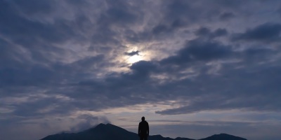 man standing alone on mountainside in dim light