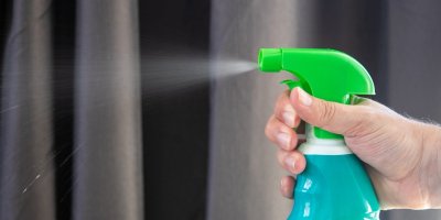 image of a hand holding and spraying disinfectant from a bottle