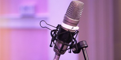 closeup image of a podcast microphone with a blurred purple background