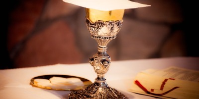 a chalice with a cross on it, prepared with the eucharist for communion