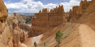 A wilderness setting on a sunny day in Bryce Canyon, Utah, with a high desert trail descending through towering rock formations