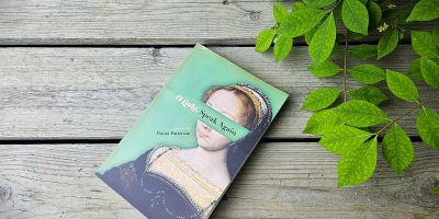The poetry book O Lady, Speak Again, by Dayna Patterson, placed diagonally on a porch near a leafy plant