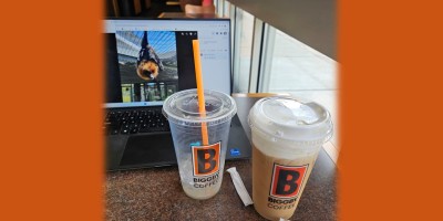 Grace, a flying fox bat as seen on a laptop screen at a Biggby Coffee shop behind two plastic cups, one empty and one full