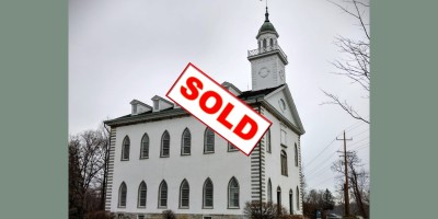 the Kirtland Temple, sacred site of Mormonism, on a cloudy day, marked with a "SOLD" stamp